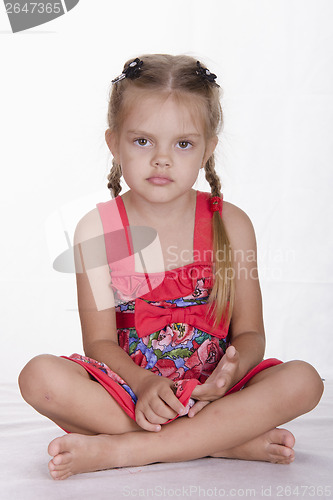 Image of Girl in dress sits and stares out the frame