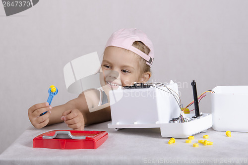 Image of Girl fun holding a wrench nut, repairing toy