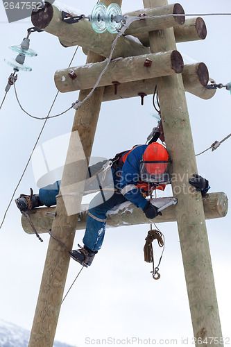 Image of electrician working on top of an electricity pylon 