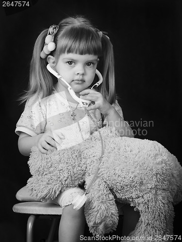 Image of Girl playing in doctor with a Teddy bear