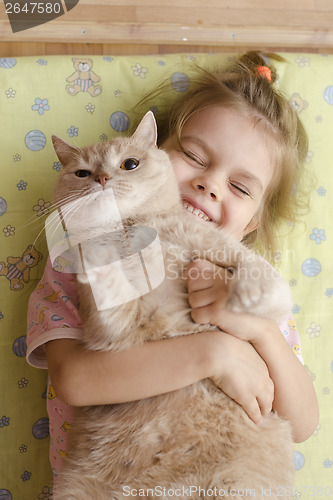 Image of little girl hugging cat lying on a mattress floor