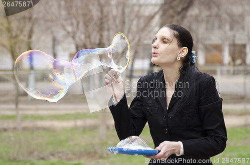 Image of girl inflates a big bubble in the street