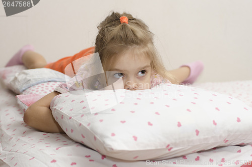 Image of girl lying and hiding his face in pillow looking right
