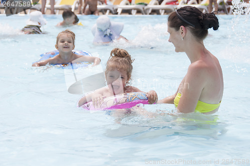 Image of mother and two daughters are swimming in a public pool