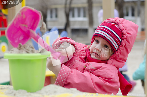 Image of little girl pours sand bucket in sandbox