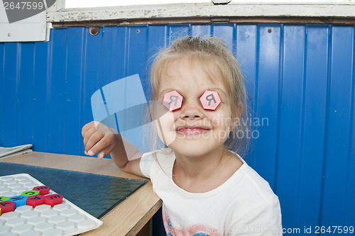 Image of Girl stuck in eyes of mosaic with letter I and smiles