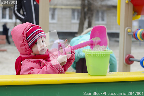 Image of little girl pours sand bucket in sandbox