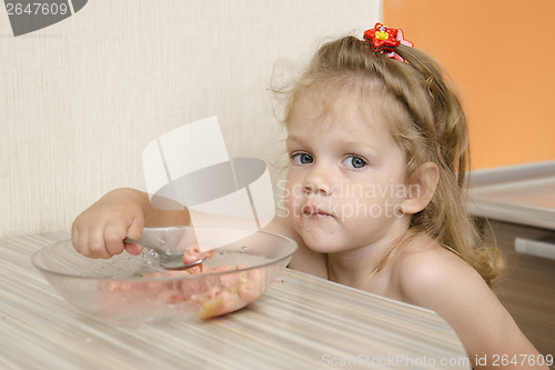Image of child with the inquiring views eats porridge