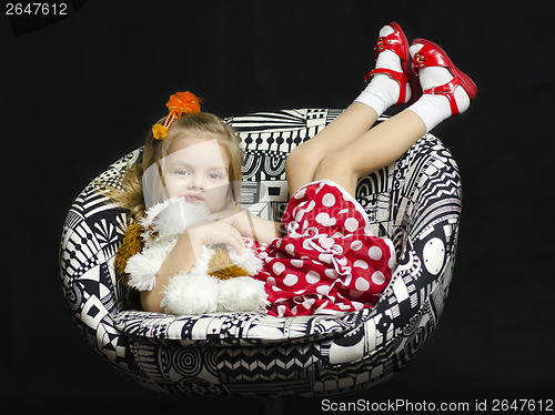 Image of little girl with a soft toy on chair