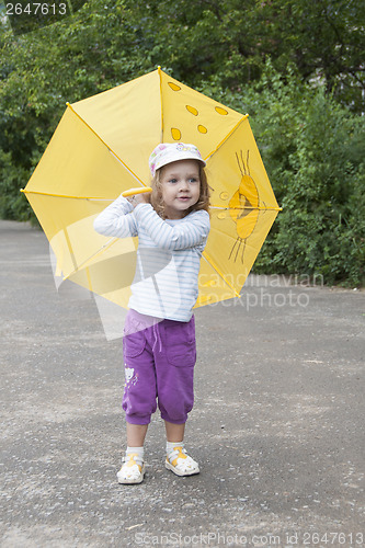 Image of Small girl standing with the yellow umbrella