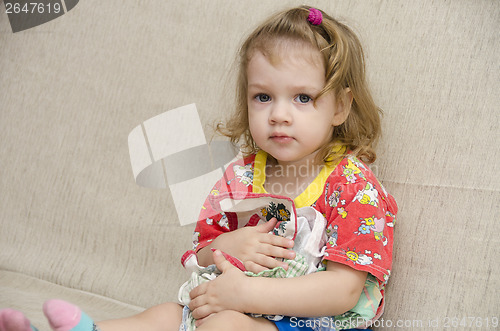 Image of  little girl was sitting on sofa with scarves in hands of