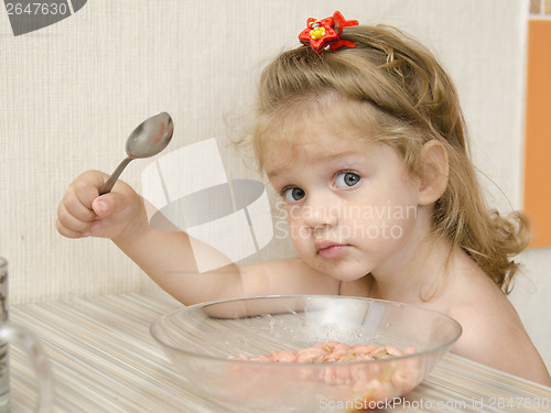 Image of child with the inquiring views eats porridge