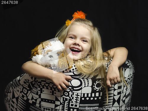 Image of little girl with a soft toy on chair