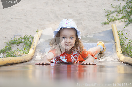 Image of Little girl climbing child of old metal slide up