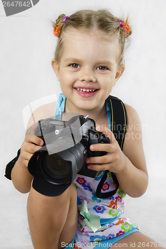 Image of merry girl keeps SLR camera
