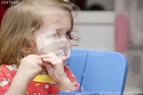 Image of girl is licking spoon, eats cake, and looks right