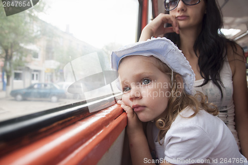Image of Sad and tired girl looks through window in tram