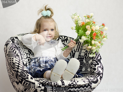 Image of little girl sitting on chair with bunch of flowers