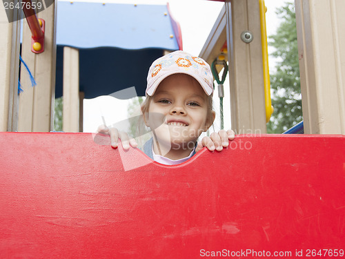 Image of girl peeks out from behind shield playing on Playground