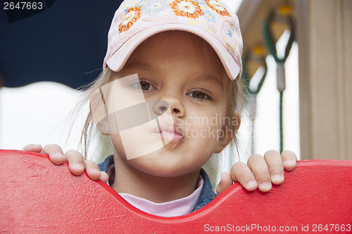 Image of girl peeks out from behind shield playing on Playground