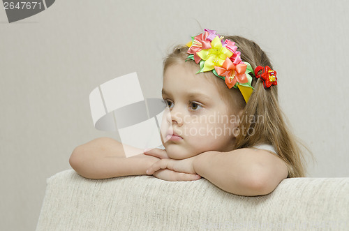 Image of Portrait girl that looks thoughtfully left leaning his elbow on back of sofa