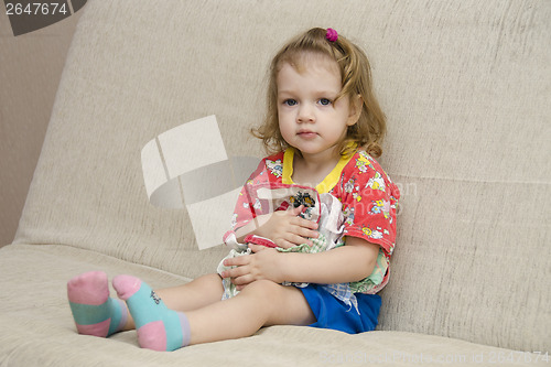 Image of  little girl was sitting on sofa with scarves in hands of
