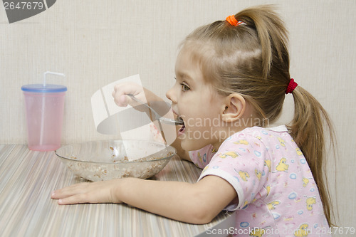 Image of Girl eating porridge sitting at table