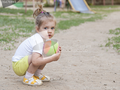 Image of Little girl sitting on his haunches with a ball Playground