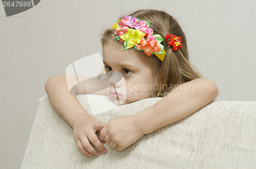 Image of Portrait girl that looks thoughtfully left leaning his elbow on back of sofa