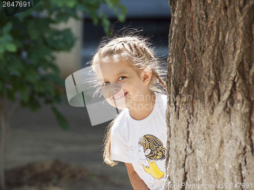 Image of child of four years peeping from behind a tree