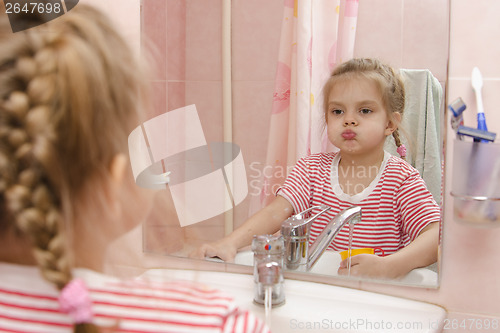 Image of Four-year-old girl rinse teeth after cleaning in bathroom