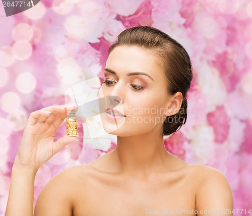 Image of beautiful woman showing bottle with golden dust