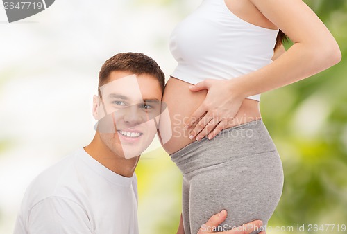 Image of happy father listening belly of his pregnant wife