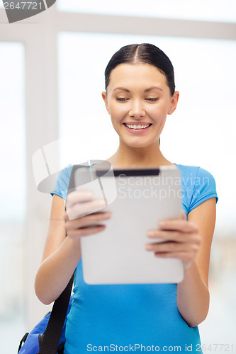 Image of smiling female student with tablet pc and bag