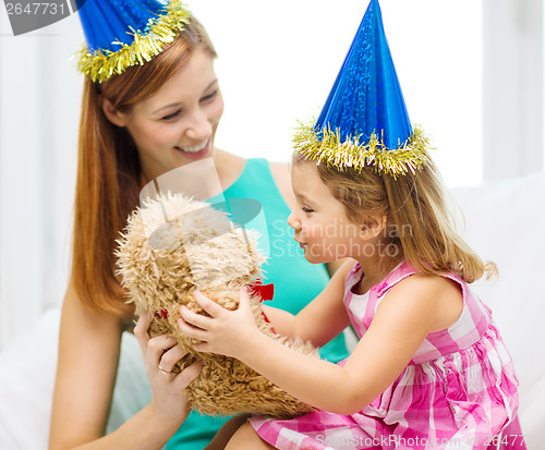 Image of mother and daughter in blue hats with teddy bear