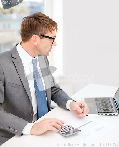 Image of businessman with computer, papers and calculator