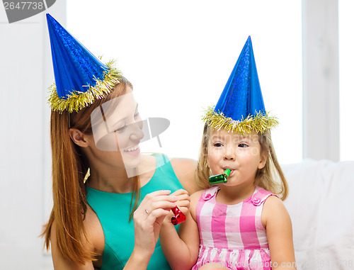 Image of mother and daughter in blue hats with favor horns