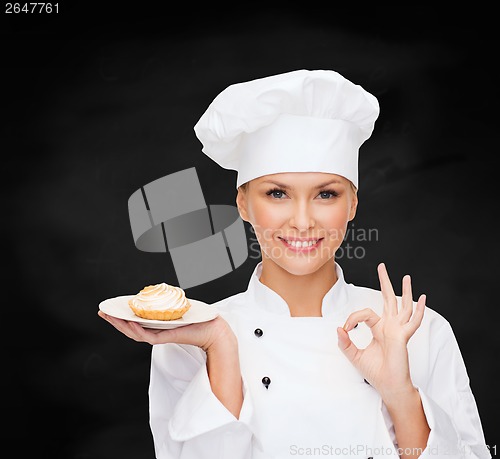 Image of smiling female chef with cake on plate