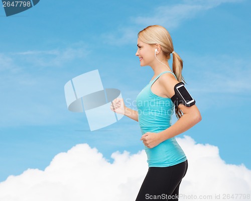 Image of sporty woman running with smartphone and earphones