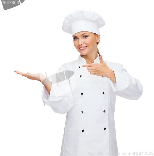 Image of smiling female chef holding something on hand