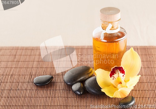 Image of essential oil, massage stones and orchid flower