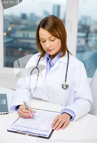 Image of busy doctor with laptop computer and clipboard