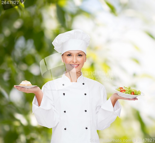 Image of smiling female chef with salad and cake on plates