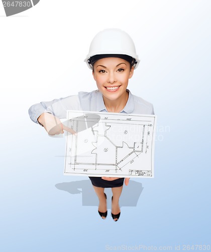 Image of businesswoman in helmet showing with blueprint