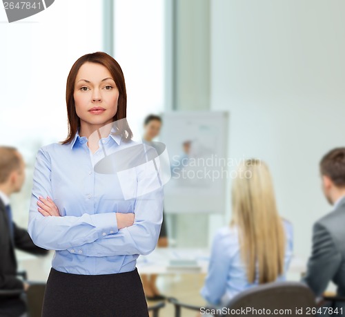 Image of smiling businesswoman with crossed arms at office