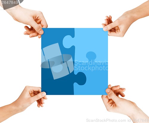 Image of four hands connecting puzzle pieces