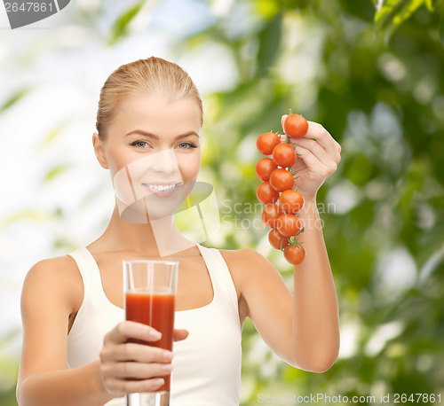 Image of woman holding glass of juice and tomatoes