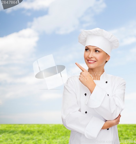 Image of smiling female chef pointing finger to sonething