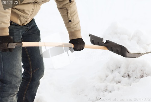 Image of closeup of man shoveling snow from driveway