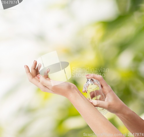 Image of woman hands spraying perfume